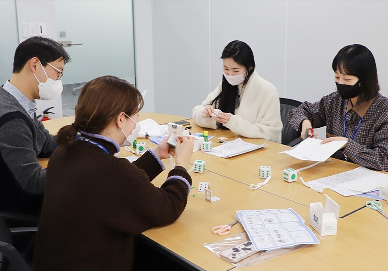 Employees make Braille cubes that were donated to Changemakers, a social welfare organization. The Braille cubes are used as teaching tools for visually impaired children that turn learning Braille into a fun game. The company conducts volunteer activities to support visually impaired children every year. (Toray Advanced Materials Korea Inc.)