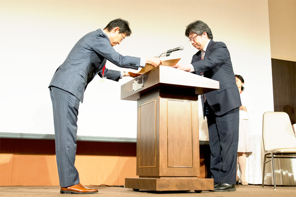 表彰式にて、経済産業省製造産業局の福島審議官から表彰状を授与される木村所長