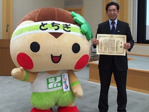 表彰状を手に桑原課長。栃木県マスコットキャラクター「とちまるくん」と受賞の喜びを分かち合いました