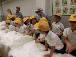 工場見学でＯＦＳ社の生産する綿に触れる子供たち