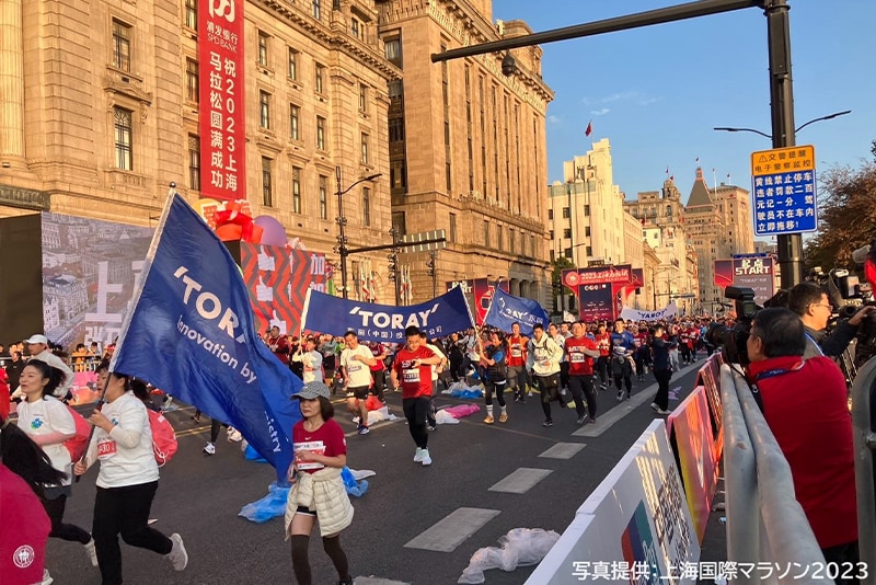 東レの旗を持って上海の街を走る東レチームのランナーたち